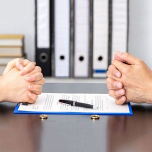 Two individuals sitting at a table, hands placed on a paper, discussing divorce proceedings - Lusby Law P.A